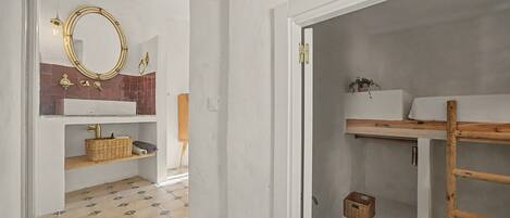 Een badkamer met een witte wastafel, een spiegel, een handdoekhouder en een houten plank.