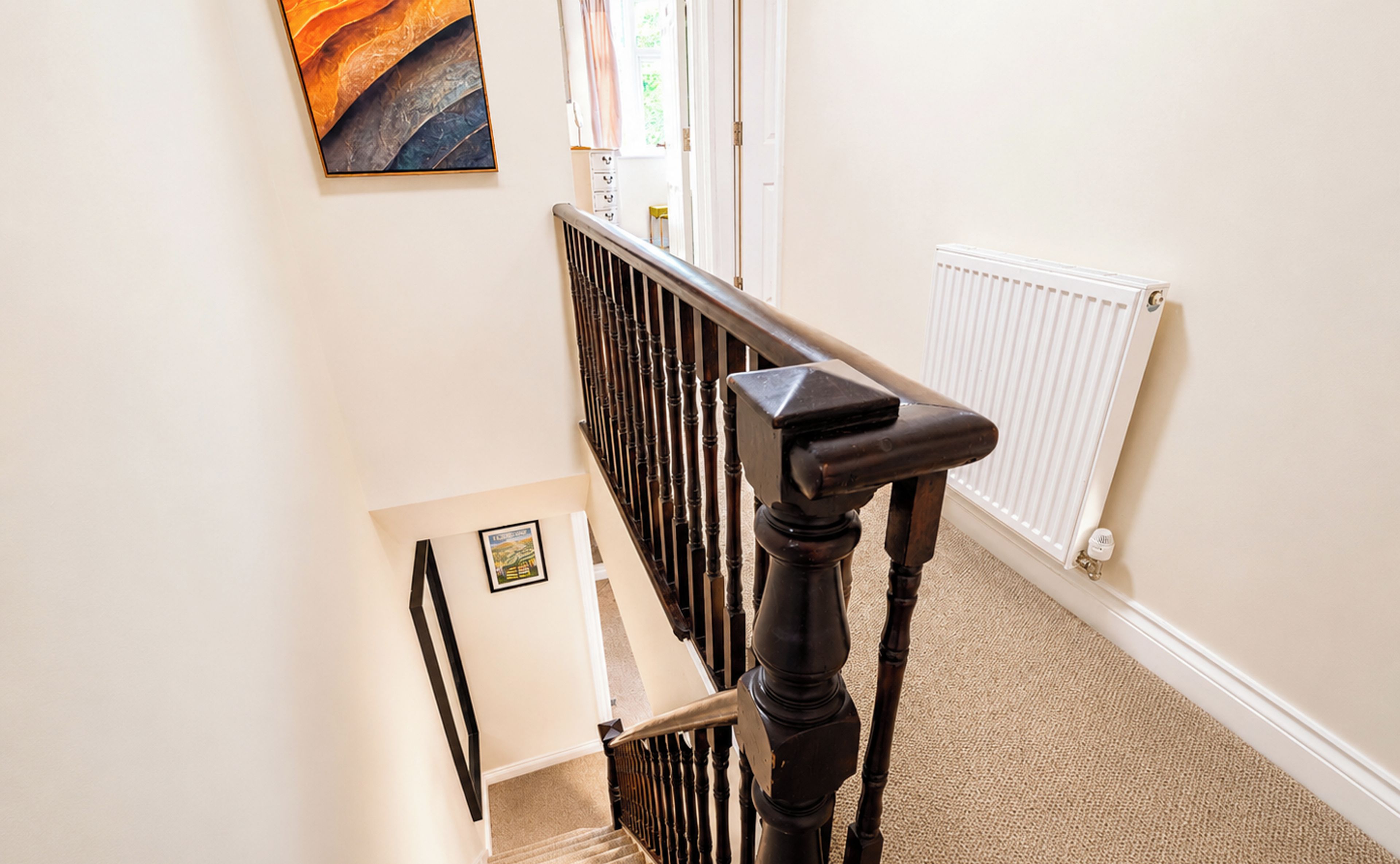 A staircase with a wooden handrail and a white radiator on the wall.