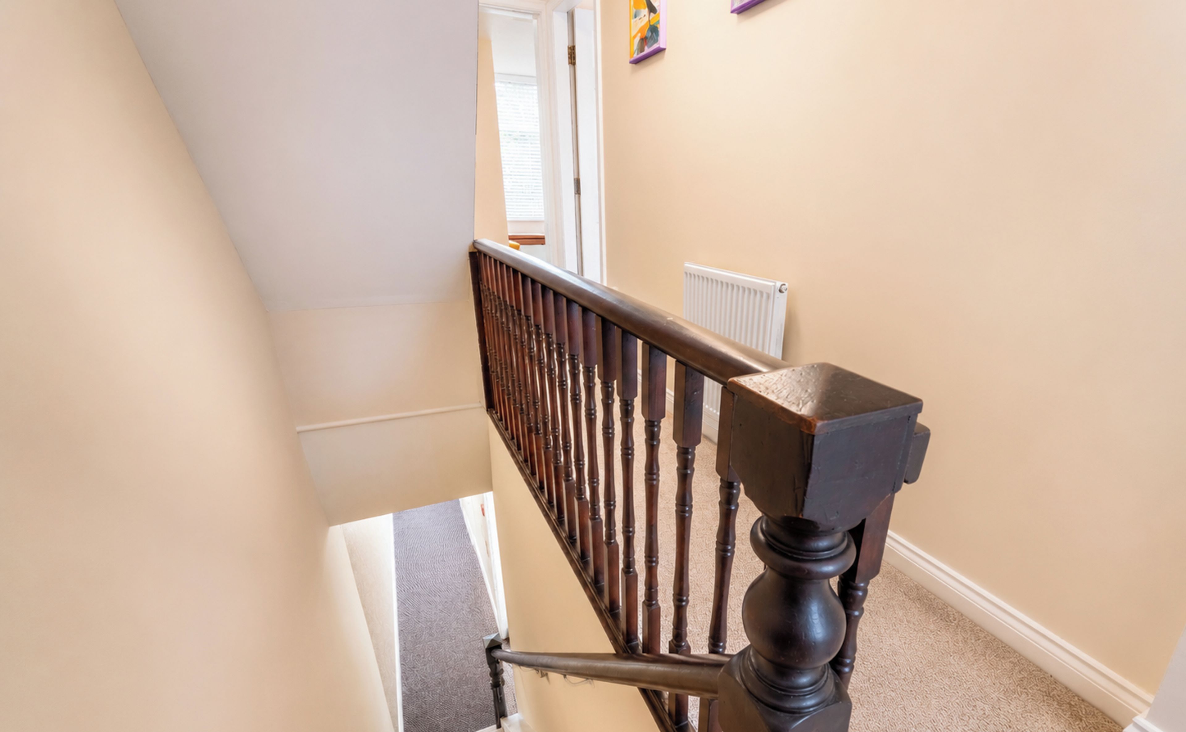A staircase with wooden balusters and a handrail, leading to an upper floor.