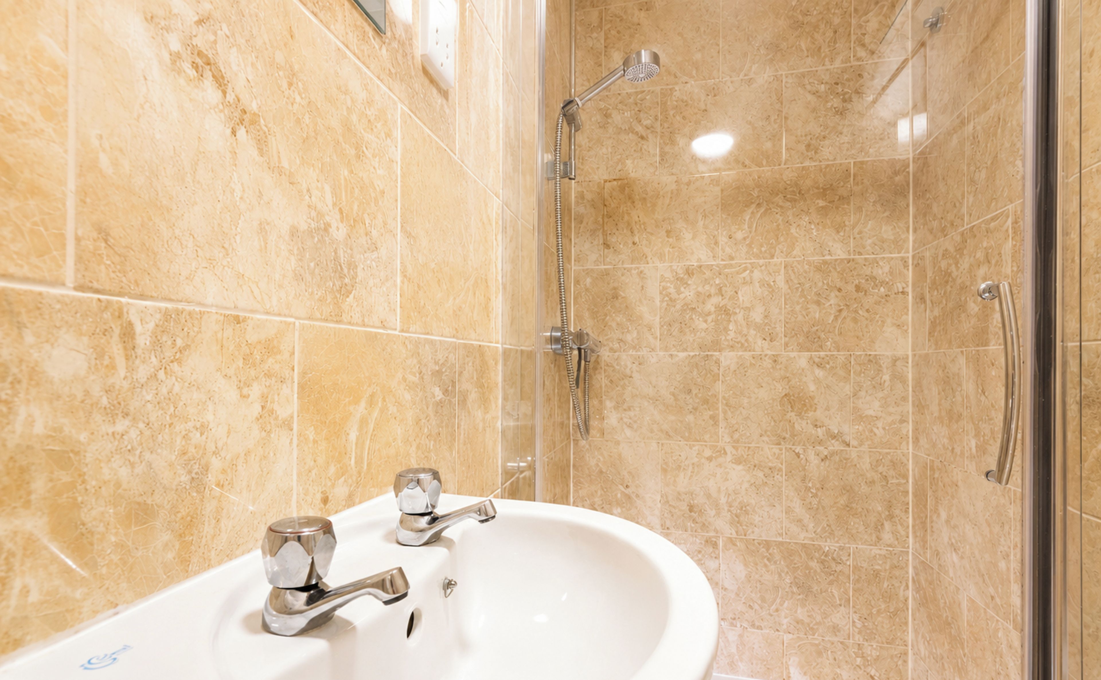 A bathroom with a sink, mirror, and shower.