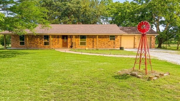 A single-story brick house with a front garage, a well-maintained lawn, and a windmill. - Pleasant Farms - A Luxurious Retreat with Tree House in charming Wharton (Wharton)