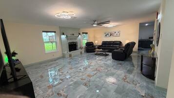 A spacious living room with a fireplace, leather sofas, and a flat-screen TV.