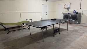 A room with a ping pong table, a green hammock, and a washing machine. - Pleasant Farms - A Luxurious Retreat with Tree House in charming Wharton (Wharton)