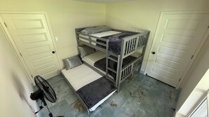 Habitación con literas, un ventilador, dos puertas y suelo de baldosas.