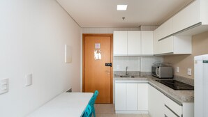 A compact kitchen with white cabinets, a microwave, and a sink. - Flat Near Flamboyant Mall - Bft3207 (Goiânia)