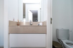Casa de banho com sanita, bidé e espelho.