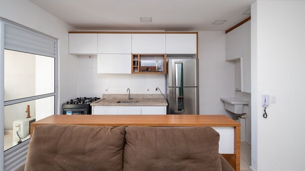 Una cucina moderna con mobili bianchi, un frigorifero in acciaio inossidabile, un forno a microonde e un piano di lavoro in legno.