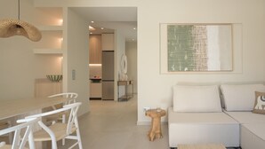 En moderne stue med en sofa, et spisebord med stole og et køkken i baggrunden.