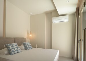 Une chambre à coucher avec un lit, des oreillers, un climatiseur fixé au mur et un luminaire au plafond.