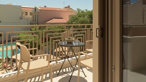 A balcony with a table and chairs, overlooking a swimming pool and buildings. - Infinity Suites 2, By Hellocrete (Rethymno)