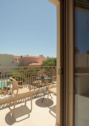 Ein Balkon mit Tisch und Stühlen, mit Blick auf einen Pool und Gebäude.