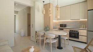 A modern kitchen with a central island, pendant lights, and built-in appliances. - Infinity Suites 2, By Hellocrete (Rethymno)