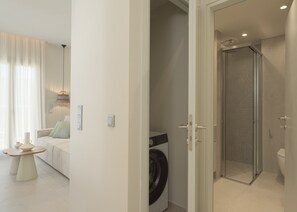 Ein modernes Interieur mit Wohnbereich, Waschmaschine und einer Duschkabine aus Glas.