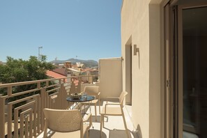 Een balkon met een tafel en stoelen, en een uitzicht op gebouwen en heuvels op de achtergrond.