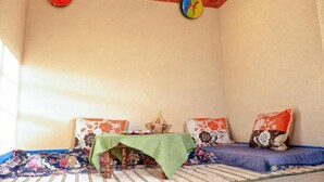 Een kamer met een bed, een tafel met een groene tafelkleed en twee kussens met bloemmotieven.