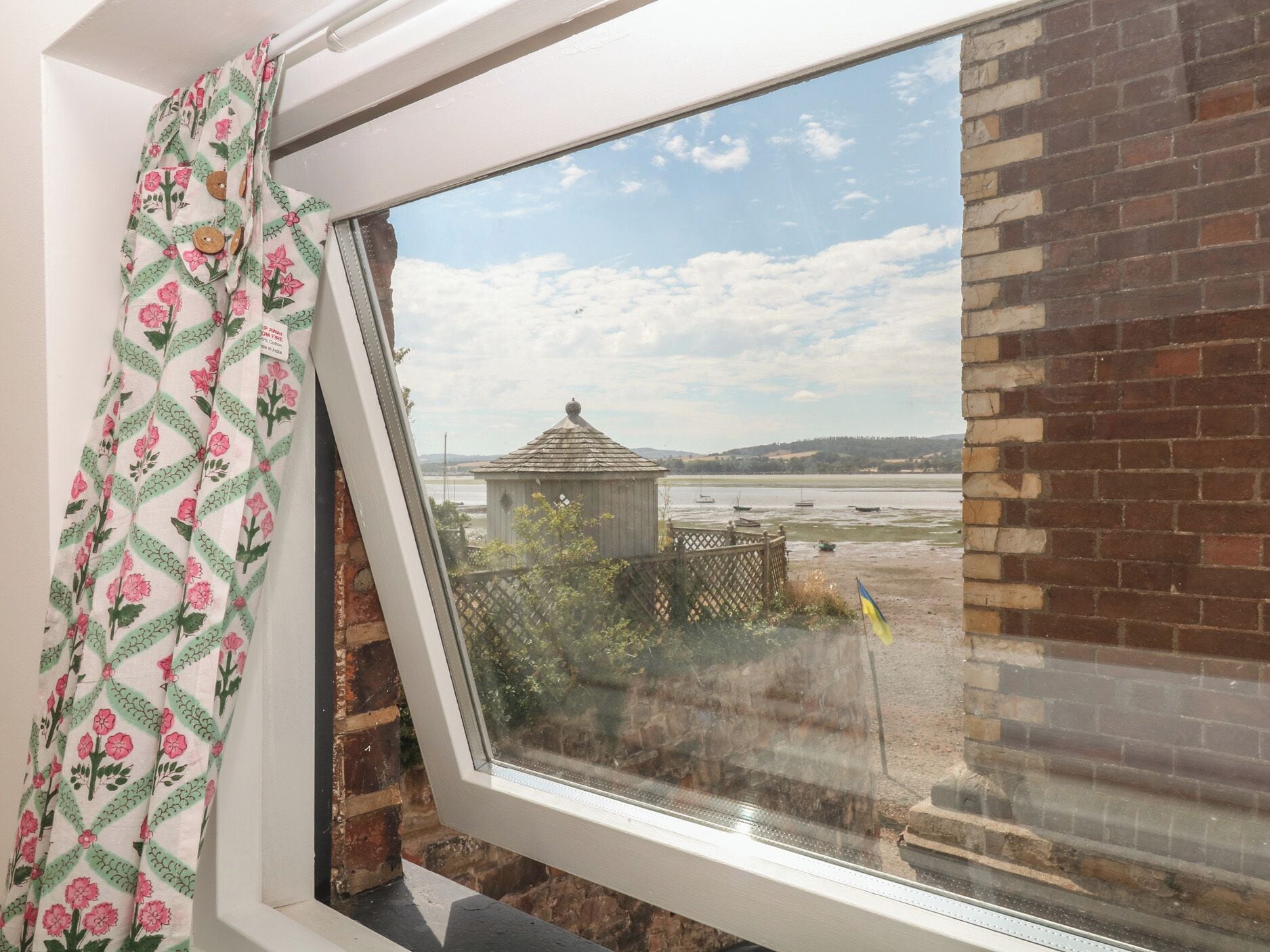Ein Fenster mit Blick auf eine Ziegelwand und eine kleine Holzkonstruktion.