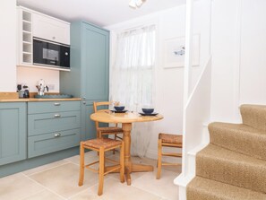 A compact kitchen with a microwave, cabinets, and a dining area with a table and chairs. - Alongside (Exmouth)