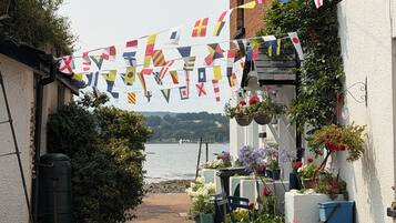 A narrow pathway leading to a building with a view of the sea. Flags are strung across the pathway.
