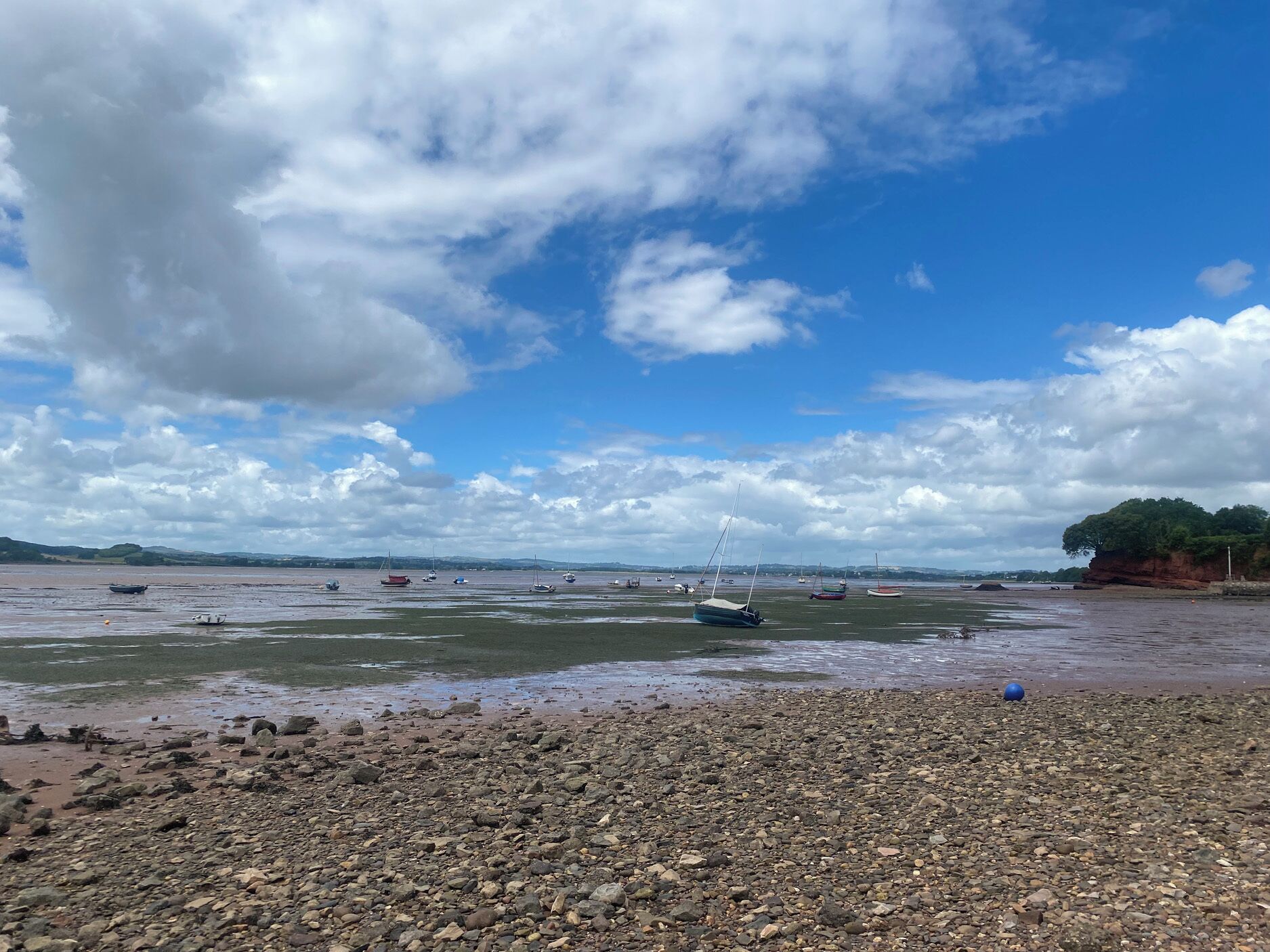 A rocky beach with boats and a clear sky.