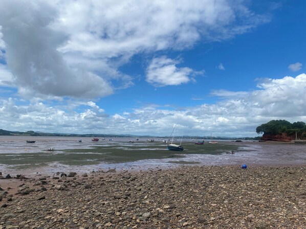 A rocky beach with boats and a clear sky. - Alongside (Exmouth)