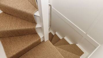 A staircase with carpeted steps and a white handrail.