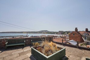 A coastal view with a bench, a flower bed, and a view of the sea and buildings. - Host Stay Casa Formentera (Scarborough)