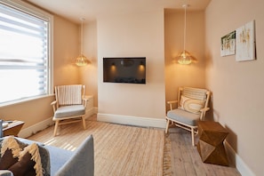 A room with two wooden chairs, a television mounted on the wall, and a woven rug on the floor. - Host Stay Casa Formentera (Scarborough)
