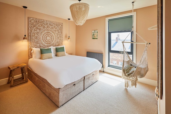 A bedroom with a large bed, a hanging chair, a tapestry, and a view of the city through a window. - Host Stay Casa Formentera (Scarborough)