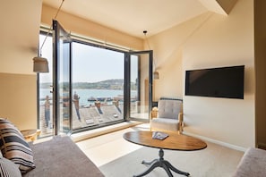 A modern living room with a large sliding glass door leading to a balcony with a view of a waterfront. - Host Stay Casa Formentera (Scarborough)