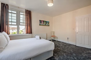 Une chambre d’hôtel avec un lit, une chaise, un radiateur, un tableau et une porte.