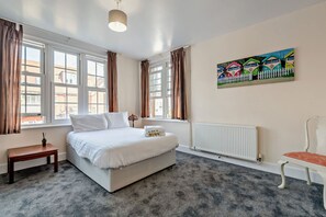 Um quarto com cama, mesa de cabeceira, radiador e um quadro na parede.
