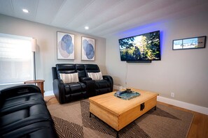 Ein Wohnzimmer mit einer schwarzen Ledersofa, einem Holztisch und einem flachbildfernseher an der Wand.