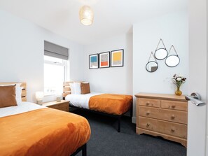 A hotel room with two beds, a dresser, a mirror, and artwork on the wall. - 23 Trafalgar Road (Scarborough)