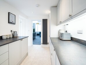 A modern kitchen with white cabinetry, a patterned floor, and a view into a dining area. - 23 Trafalgar Road (Scarborough)