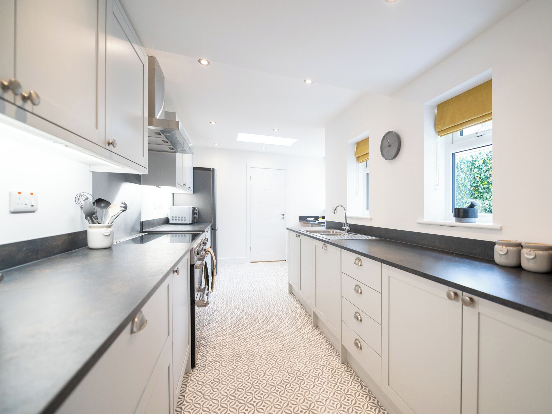 Een moderne keuken met witte kastjes, een zwart aanrecht en een vloer met een patroon.