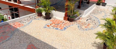 A rooftop terrace with a mosaic floor, potted plants, and outdoor seating.