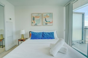 Una habitación de hotel con una cama, una ventana, una lámpara y dos obras de arte colgadas en la pared.