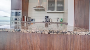 A modern kitchen with a stainless steel range, a built-in microwave, and a granite countertop. - Wanderlust Suites (Toronto)