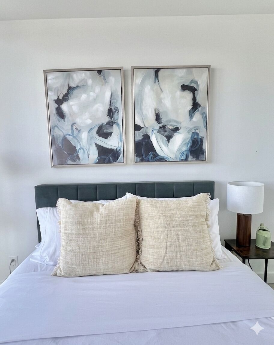 Un lit avec une literie blanche et deux oreillers beige, une tête de lit rembourrée de couleur vert foncé et une table de chevet avec une lampe et un vase vert.