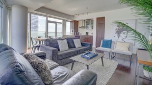 A modern living room with a sofa, coffee table, and a dining area with chairs. - Wanderlust Suites (Toronto)