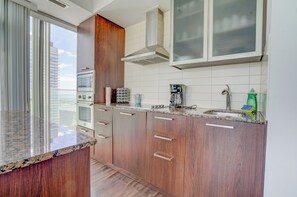 Una cocina moderna con armarios de madera, encimera de granito, extractor de acero inoxidable y un amplio ventanal con vistas a la ciudad.