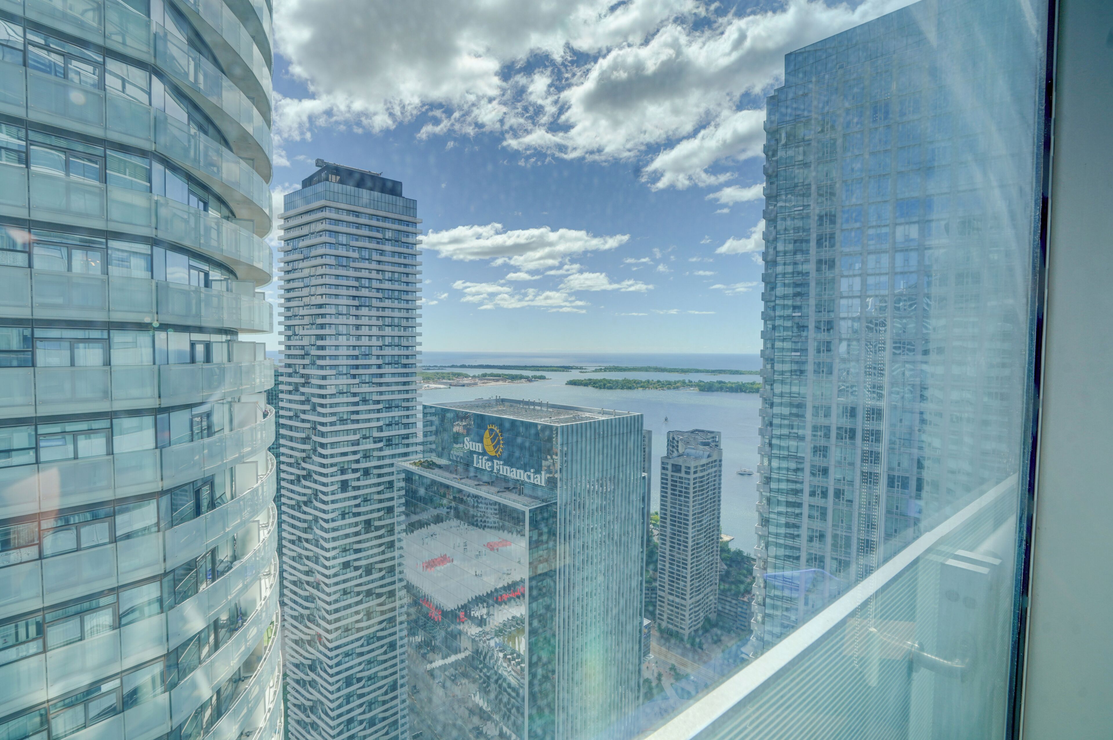 A high-rise building with a glass facade, a view of a body of water, and a clear sky.