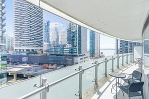 A balcony with a glass railing overlooking a cityscape with modern buildings.