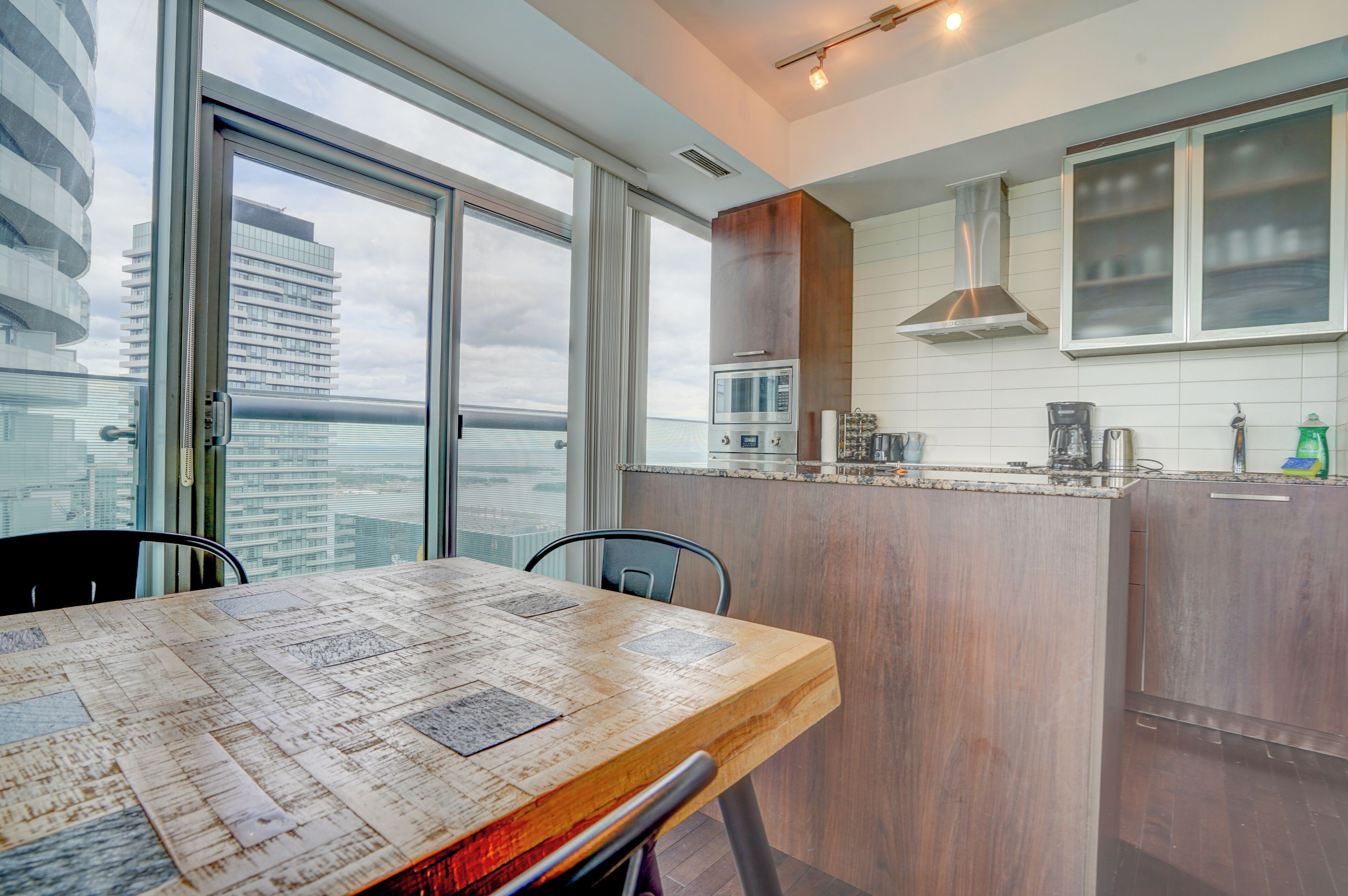 A modern kitchen with a dining area, large windows, and a view of the cityscape.