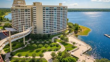 A large, circular hotel with multiple floors, a waterfront promenade, and a pedestrian bridge.
