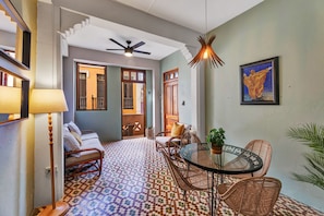 A room with a patterned floor, wicker furniture, a ceiling fan, and a painting on the wall. - San Cristóbal View | 2BR in Old San Juan (San Juan)