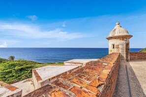 A coastal view with a stone wall and a small dome structure overlooking the sea. - San Cristóbal View | 2BR in Old San Juan (San Juan)
