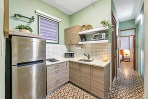 Eine kleine Küche mit Kühlschrank, Mikrowelle und Spüle.