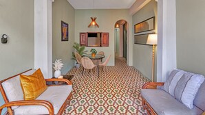 Ein Zimmer mit Essbereich, zwei Sofas, einem Tisch mit Stühlen und einem gemusterten Boden.