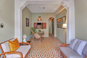 Ein Zimmer mit Essbereich, zwei Sofas, einem Tisch mit Stühlen und einem gemusterten Boden.